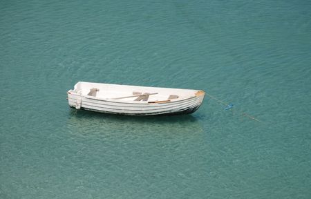 An old white painted wooden rowing boat in a southern European harbour  の写真素材