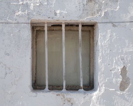 A barred window in a whitewashed wall on old building in Puglia, southern Italy 
