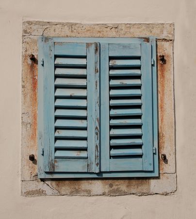Blue wooden shutters cover a window in an old building in the Slovenian coastal town of Izolaの写真素材