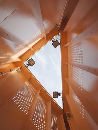 Looking up through the interior of an orange metal structure 