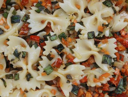 A salad of farfalle pasta dressed in olive oil with sun dried tomatoes, garlic, onion, carrots and pineapple sage の写真素材