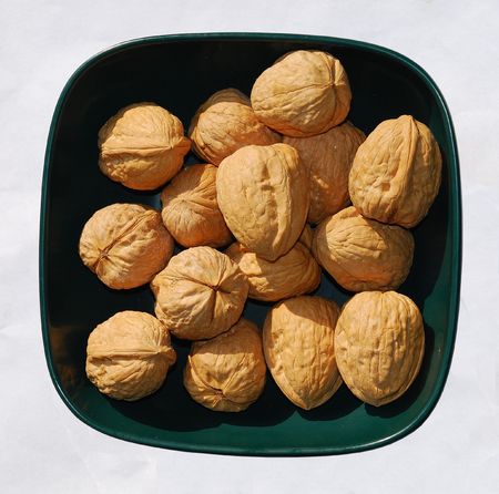 A bowl of unshelled walnuts in natural lighting の写真素材