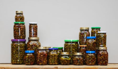 A collection of home made organic olives in oil in glass jars 