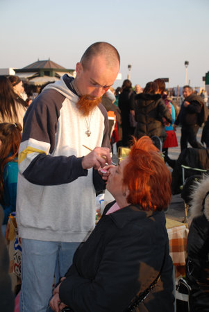 Venice, Italy, 02.21.09: A face painter paints the face of a woman during the Venice Carnivalのeditorial素材