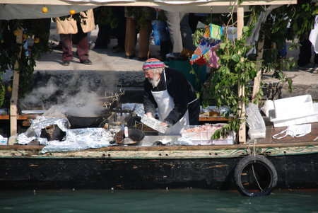 Venice, Italy, 02.21.09: A chef fries fish on a canal boat for a queue of hungry customers at the Venice Carnivalのeditorial素材