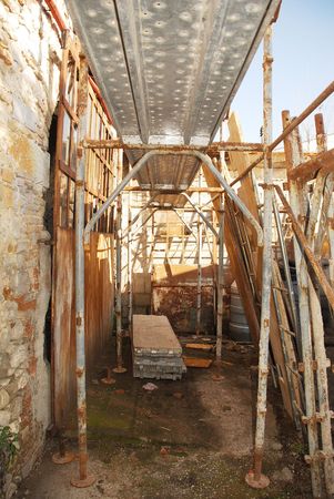 Old rusted scaffolding outside a stone farmhouse buildingの写真素材