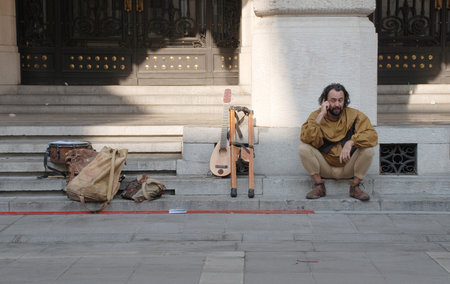 Udine, Italy -  September 17th 2011 - A street musician dressed in medieval costume takes a rest from performing and chats on his mobile phone during the 2011 annual Friuli Doc (Udine) celebration of locally produced food, drinks and crafts  (Friuli Doc)のeditorial素材