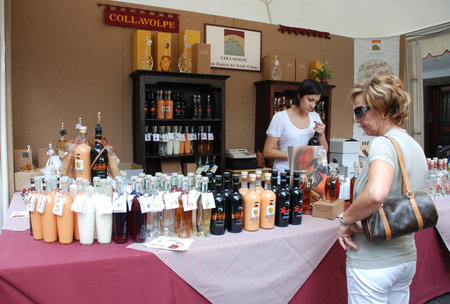 Udine, Italy -  September 17th 2011 -  A selection of locally produced alcoholic drinks on display at a street stall during  Friuli Doc . The potential customer is being served a free sampleのeditorial素材