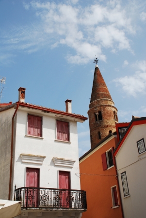 The 11th century belltower in Caorle, in the Veneto region of Italy, with historic foreground buildings.の写真素材