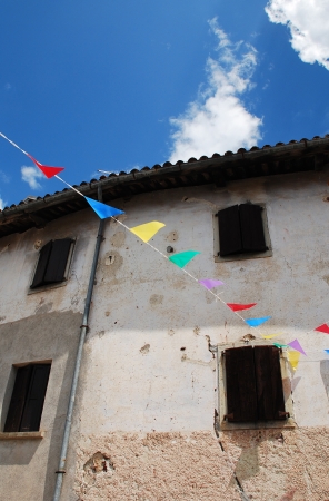 A disused rural building in a village in Friuli, north east Italy. It is decorated in bunting in celebration of the annual village fete.の写真素材
