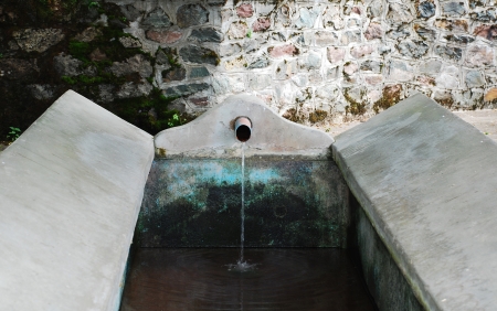 An old stone water trough in the north east Italian village of Ligosullo  It was used for laundry washing and has a running water source drawn from a nearby stream and is covered by a roof の写真素材