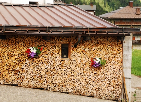 Wood for winter burning stacked up neatly at the side of a house の写真素材