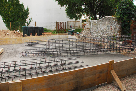 Steel reinforcement cage used in the construction of building foundations  The foundation site is surrounded by wooden shuttering and the steel cages are in the process of being laid out before the concrete is poured  Radon Iglus can be seen in the backgrの写真素材