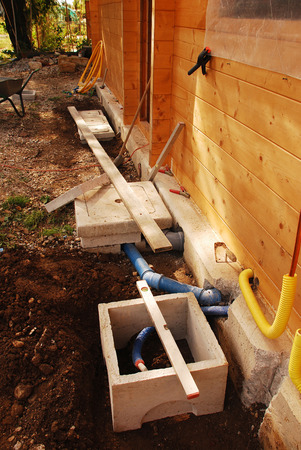 Sewage  left  and water  right  inspection chamber or wells on the building site of a newly constructed wooden  fir  house の写真素材