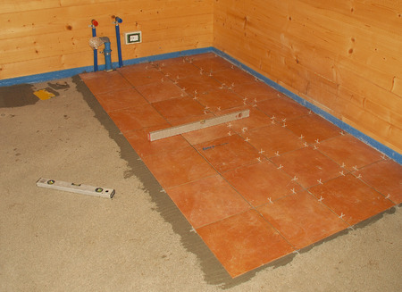 A concrete floor in a newly built wooden  for  house  Floor tiling adhesive has been applied and floor tiles laid  The blue foam material is protecting the wood from the concrete and adhesives  の写真素材