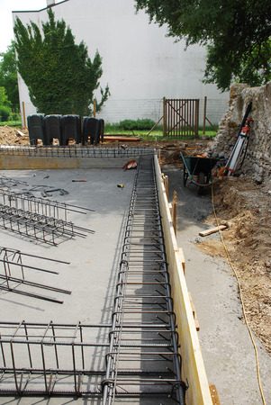 Steel reinforcement cage used in the construction of building foundations  The foundation site is surrounded by wooden shuttering and the steel cages are in the process of being laid out before the concrete is poured の写真素材