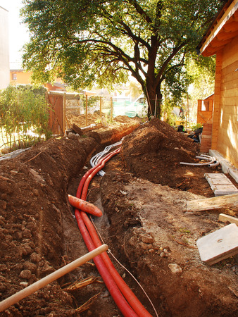 A utilities trench at the side of a newly build wood  fir  house  The trench carries the conduits for gas, water, electric, sewage and phone servicesの写真素材