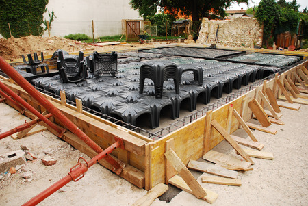 A house foundation site with steel reinforcement cages and radon iglus surrounded by wooden shuttering  The cages and iglus have been laid out ready for the concrete to be poured の写真素材