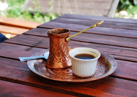 A cup of Bosnian cofee served on a copper tray from a cezve on a wooden table at a shady outdoor cafe in Travnik, Bosnia and Herzegovinaの写真素材