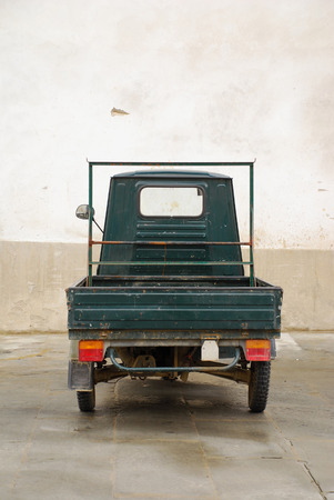 A small green ape parked in a Tuscan backstreet, Italy