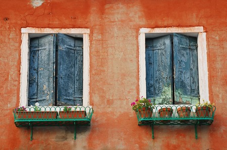 Two closed blue shuttered windows in a wall in an historic building in Muano, Venice, Italyの写真素材