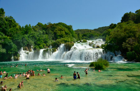 Skradin, Croatia - July 2nd 2016. Tourists swim in the waters of Skradinski Buk waterfall on the River Krka in Krka National Park, Sibenik-Knin County, Croatia. The  waterfall consists of travertine barriers and a total of 17 different water falls, it is のeditorial素材