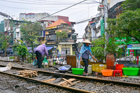 Hanoi, Vietnam - 14th December 2017. Workers from a small restaurant sort rubbish and wash dishes outside the restaurant on a residential street in central Hanoi which has grown up around the north-bound train trackのeditorial素材