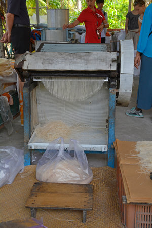 Can Tho, Vietnam - December 31st 2017. Freshly made noodle sheets are cut into noodle strips while...