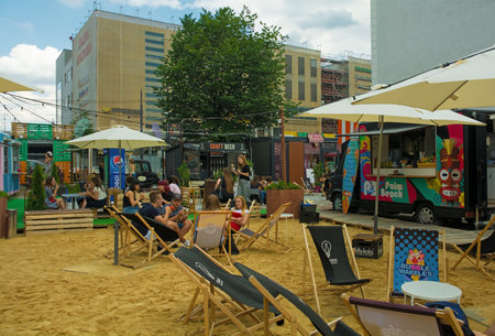Krakow, Poland - July 12th 2018. Young people relax and eat ice cream at the Dworek Street Food Park in central Krakow. The park consists of a variety of street food stalls surrounding a common seating areaのeditorial素材