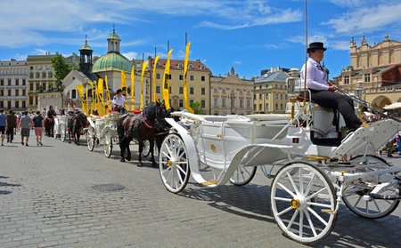Krakow, Poland - July 8th 2018. Horse driven carriages line up awaiting tourists in Rynek Glowny,...