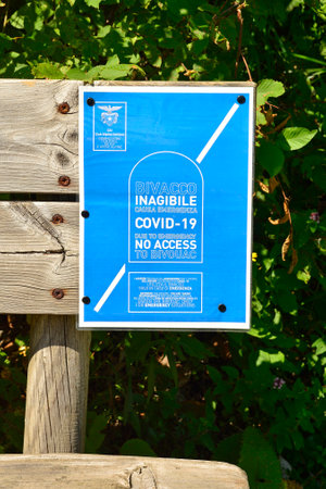 Italy - August 9th 2020. A sign in both English and Italian on a bench at the entrance to the Val Alba Nature Reserve in Friuli-Venezia Giulia warns visitors that bivouac shelters are inaccessible due to the Covid-19 pandemic, except in the event of an emのeditorial素材