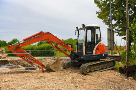 A compact crawler excavator with a rotating house platform and continuous caterpillar track on a...