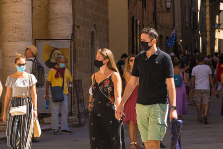 Pienza, Italy - September 6th 2020. Tourists in the historic Piazza Pio II in Pienza in Tuscany, Italy, during the COVID-19 pandemic. At this time, mask use is compulsory in the historic centre, although not everyone is complying with the rule or wearing のeditorial素材