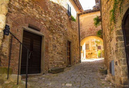 A stone archway across a quiet residential street in the historic medieval village of Montefioralle near Greve in Chianti in Florence province, Tuscany, Italyの写真素材