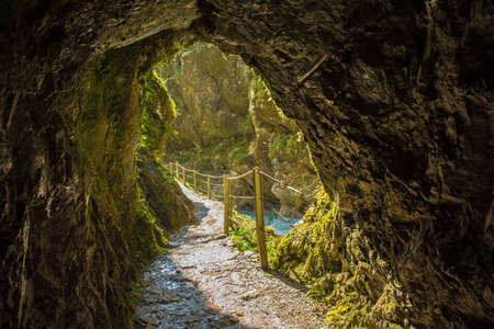 The footpath along the Tolminka River which flows through Tolmin Gorge cuts through a rock tunnel in the Triglav National Park, north western Sloveniaの写真素材