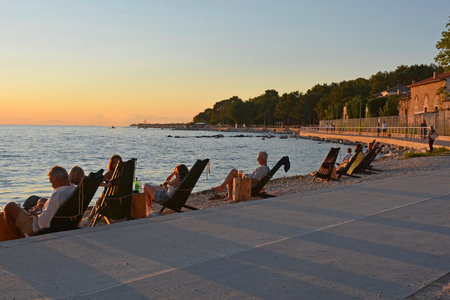 Porec, Croatia- July 10th 2021. Tourists and locals enjoy a sundowner drink at a beach bar outside in the historic medieval coastal town of Porec in Istria, Croatiaのeditorial素材