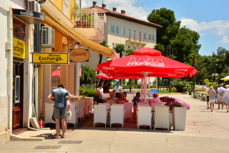 Porec, Croatia- July 10th 2021. Customers sit outside a waterfront restaurant in historic medieval coastal town of Porec in Istria, Croatiaのeditorial素材