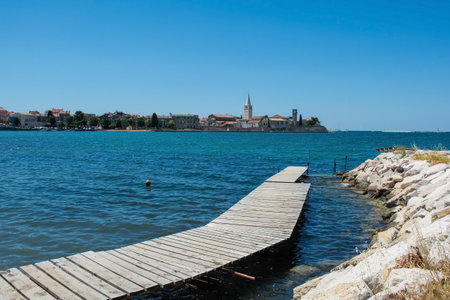 The historic medieval coastal town of Porec in Istria, Croatia, seen from the shore just north of the old town. A wooden boardwalk is in the foregroundの写真素材