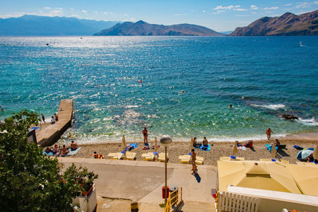 Baska, Croatia - 4th September 2021. Locals and tourists enjoy the town beach in late summer in Baska, Krk island, in the Primorje-Gorski Kotar County of western Croatiaのeditorial素材