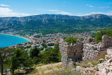 The ruins of the medieval Baska Citadel, Kastel Baska, overlooking the south Krk island town of Baska in the Primorje-Gorski Kotar County of western Croatiaの写真素材