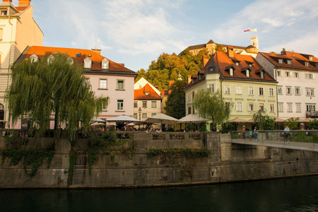 Ljubljana, Slovenia - September 3rd 2022. Restaurants and bars on the waterfront of the Ljubljanici River in central Ljubljana, Slovenia. The Fishmarket Footbridge is foreground right, and the castle tower background rightのeditorial素材