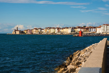 The waterfront of the historic medieval town of Piran on the coast of Slovenia. Background left is the Our Lady of Health Church and a 17th century lighthouse towerの写真素材
