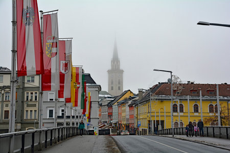 Villach, Austria - December 24th 2022. A foggy Christmas Eve on Draubrucke Bridge crossing the Drava River in the historical centre of Villach, Carinthia, Austria. The steeple of the parish church of Saint Jacob is in the distanceのeditorial素材