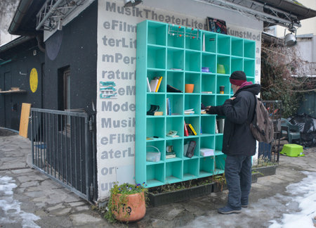 Villach, Austria - December 24th 2022. A passerby stops to look at books and other items left at a city centre book exchange in Villach, Carinthia, AUstriaのeditorial素材