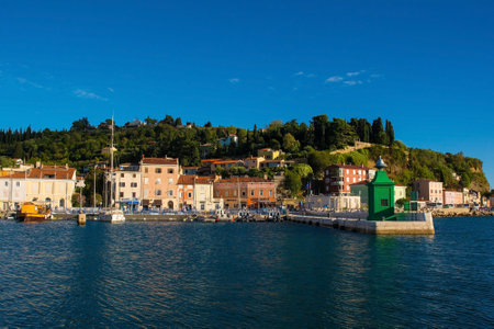 Piran, Slovenia - September 17th 2022. A small green lighthouse on the waterfront of the historic medieval town of Piran on the coast of Sloveniaのeditorial素材