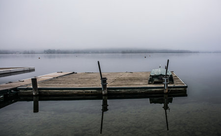 A boat jetty on a foggy winter day at Reifnitz am Worthersee on the south shore of Worthersee, or Worth Lake, in Carinthia, Austriaの写真素材