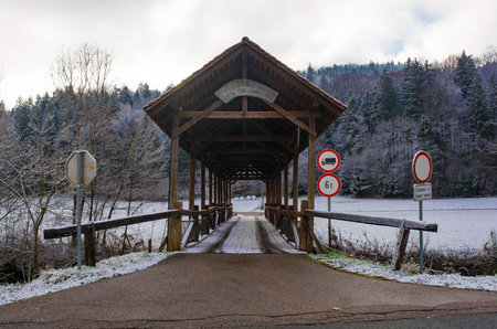 A wooden bridge crossing the Poljanska Sora River in the snowy December landscape near Hotavlje...