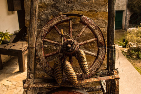 A rustic wooden wheel with pine tree cones in Poffabro, an historic medieval village in the Val Colvera valley in Pordenone province, Friuli-Venezia Giulia, north east Italyの写真素材