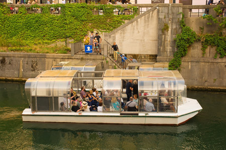 Ljubljana, Slovenia - September 3rd 2022. A tourist boat stops to pick up passengers on the waterfront of the Ljubljanici River in central Ljubljana, Sloveniaのeditorial素材