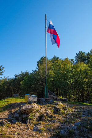 The Slovenian flag flies at the summit of Mount Skabrijel near Nova Gorica in the Primorska region of western Slovenia. A box containing the summit register is at the flagpole baseのeditorial素材